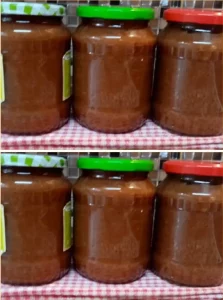 Jar of homemade apple jam with fresh apples and spreader