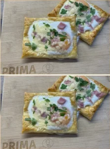 Puff pastry breakfast rolls filled with egg, ham, and cheese on a baking tray