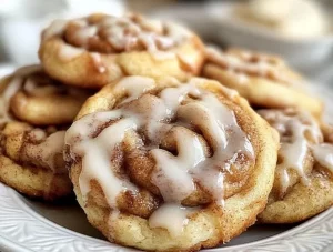 Delicious cinnamon roll cookies topped with icing on a baking sheet