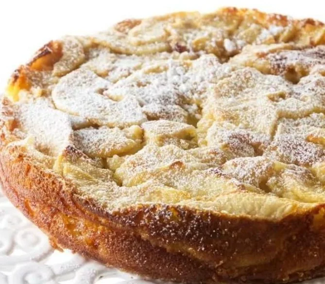 Slice of classic French apple cake with apples and a dusting of powdered sugar