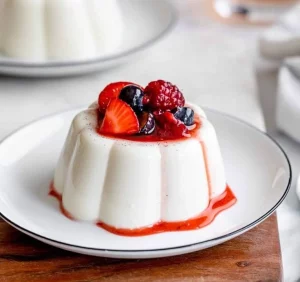 Classic vanilla panna cotta served in a dessert glass with fresh berries