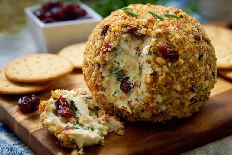 Cranberry rosemary vegan cheese ball served on a platter with crackers and nuts