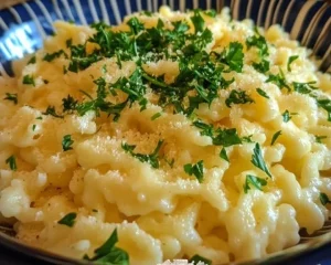 A bowl of steaming noodles garnished with fresh vegetables and herbs.