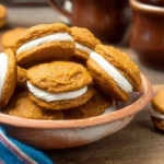 Pumpkin sandwich biscuits with cream cheese filling on a plate