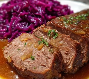 Plate of Sauerbraten served with traditional sides like red cabbage and potato dumplings.