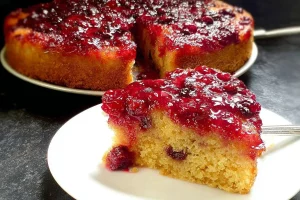 Vegan Cranberry Upside-Down Cake topped with fresh cranberries and a golden glaze.