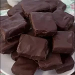 A plate of traditional Mustaccioli cookies dusted with powdered sugar.